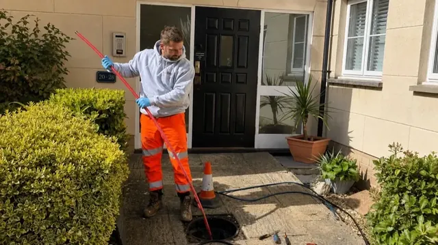 Drainage engineer unblocking an outdoor drain with high-pressure jetting equipment.